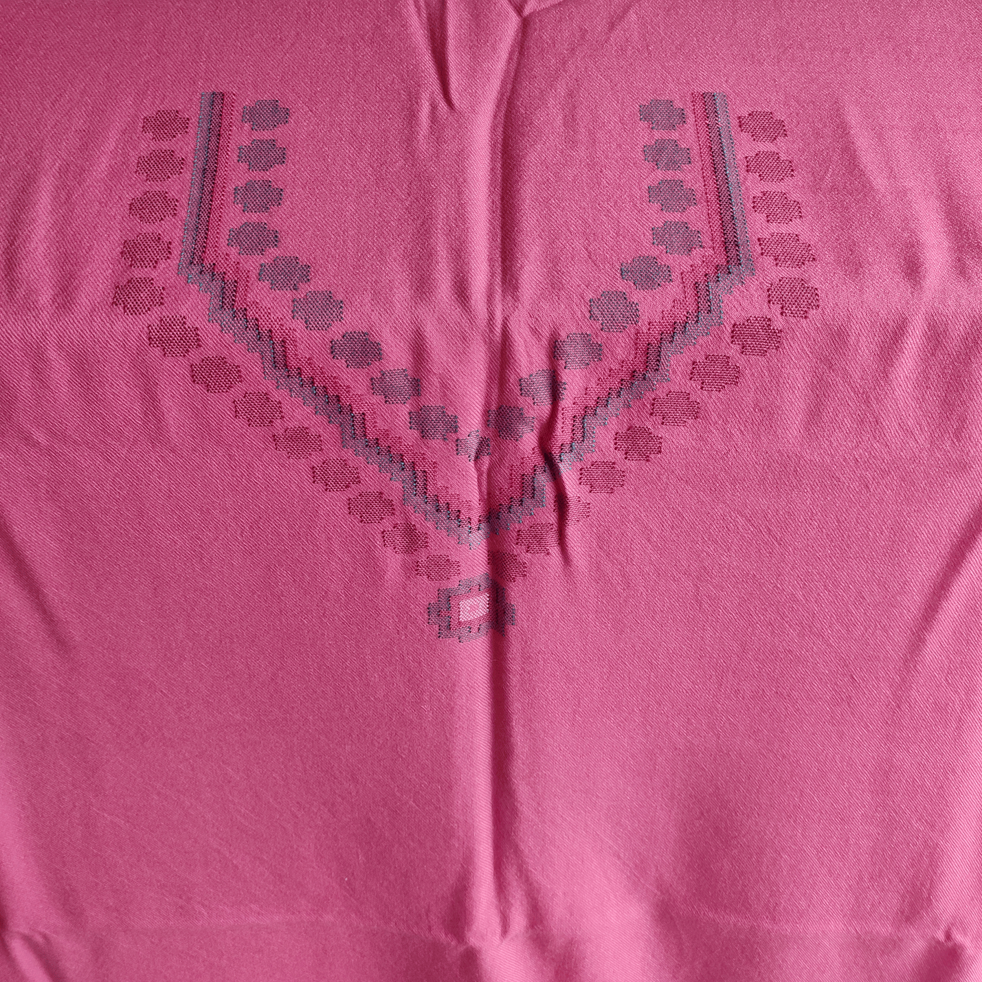 Close-up of a pink woolen suit fabric with geometric embroidery patterns